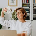 Woman working on computer with money in hand.